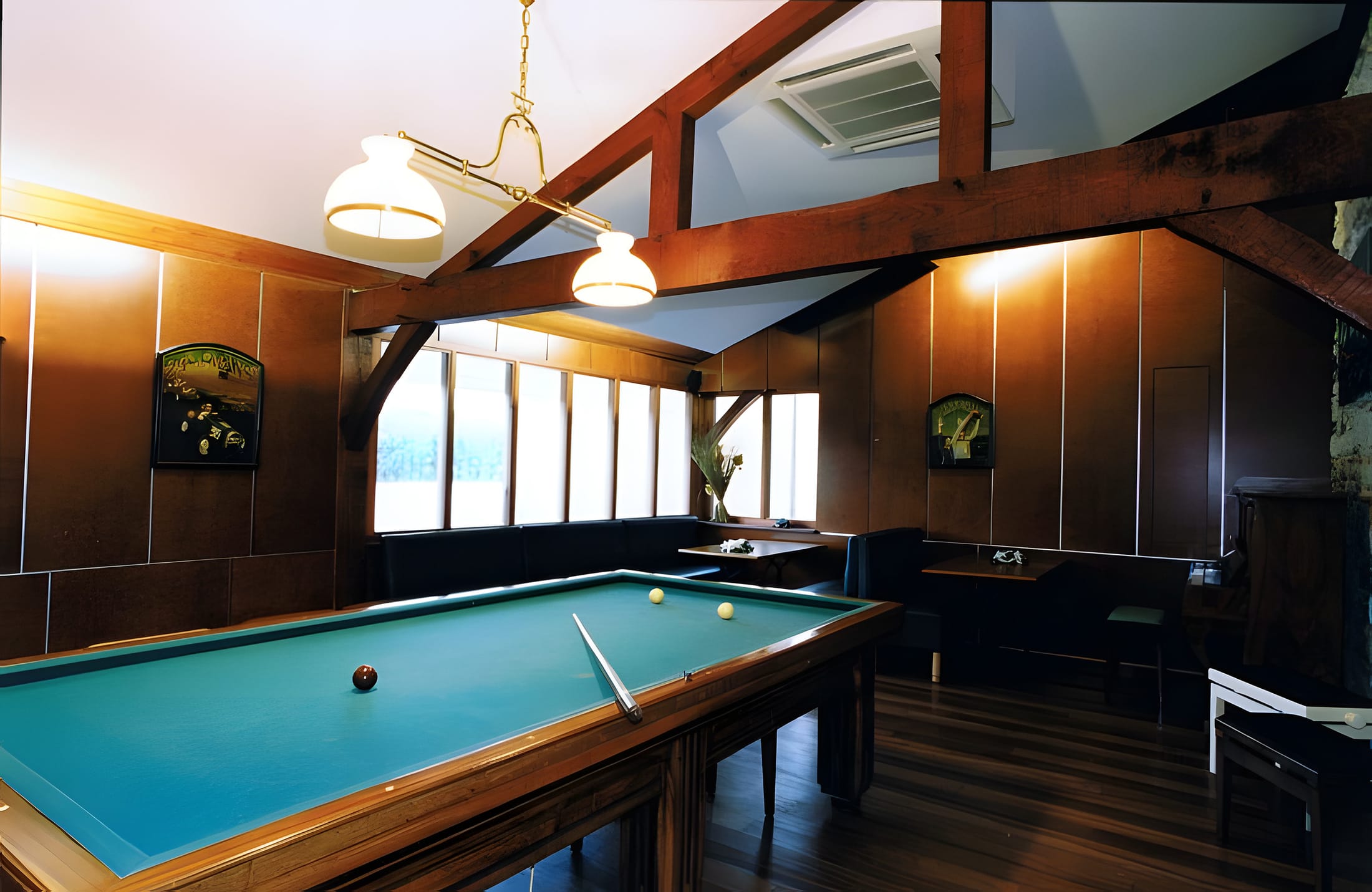 La salle de billard lambrissée, lampes à l’ancienne et banquette sous les fenêtres
